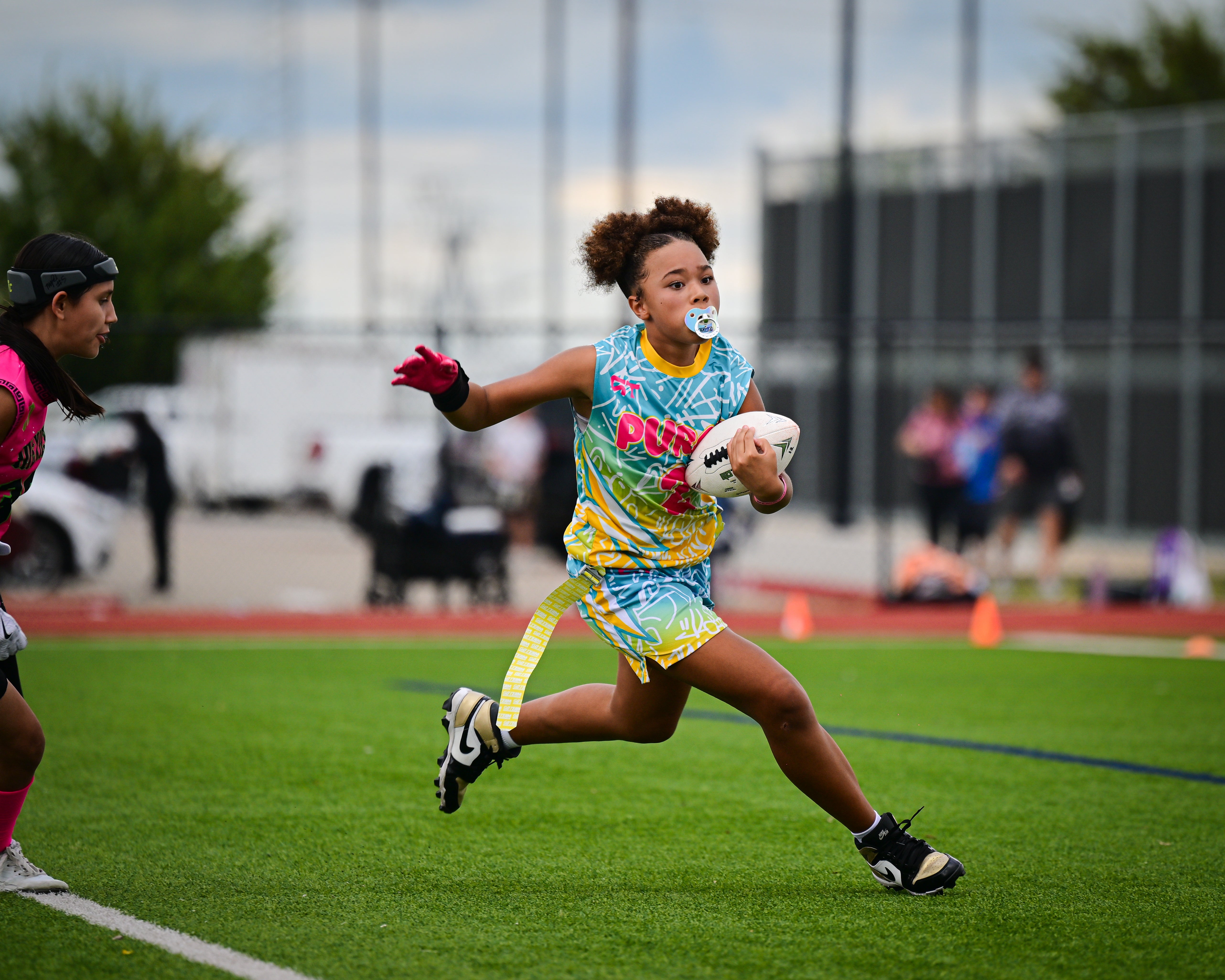 Girls high school flag football player carrying the white football