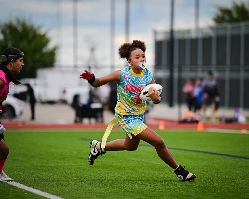 Girls high school flag football player carrying the white football